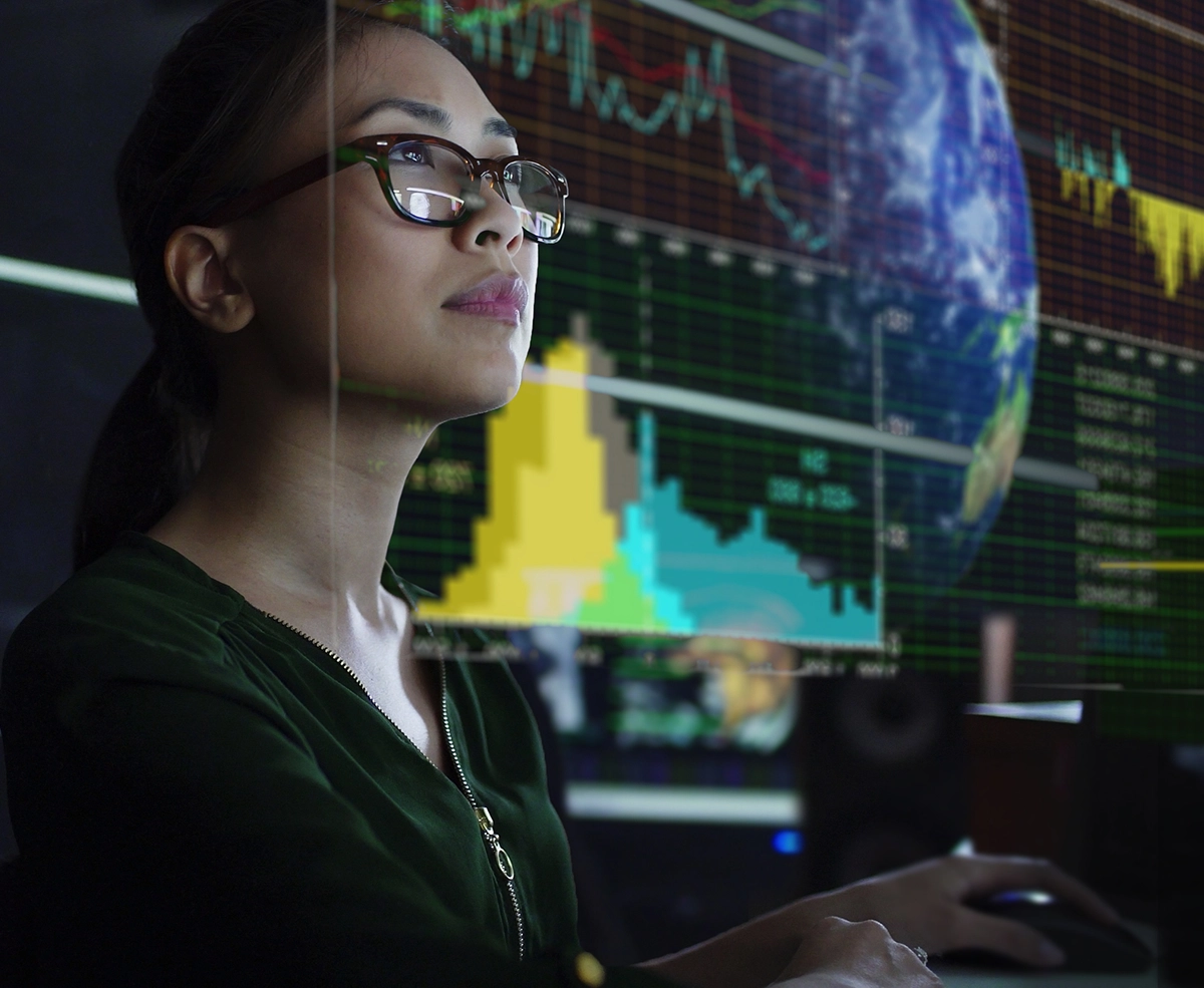 Woman at computer with data graphs in background.